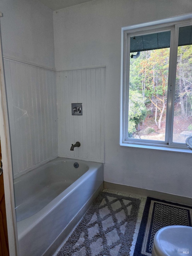 bathroom with a bathing tub, baseboards, and tile patterned floors