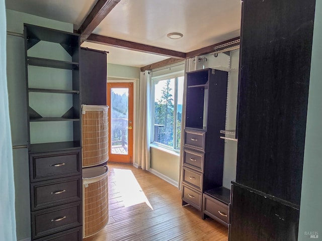 walk in closet with beam ceiling and light wood-style floors