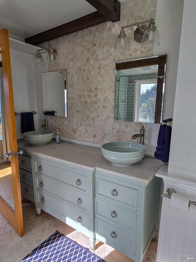 full bath featuring double vanity, a sink, and beam ceiling