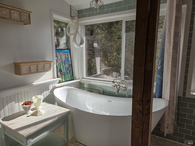 full bath with a soaking tub, a wainscoted wall, and tile walls