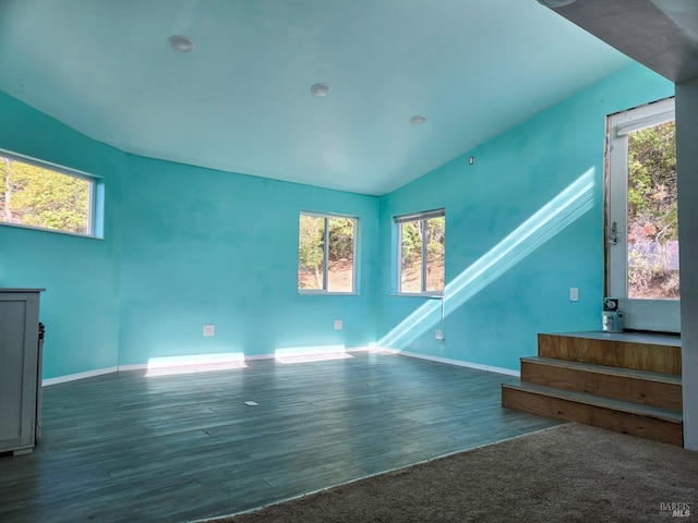 unfurnished living room featuring lofted ceiling, baseboards, and wood finished floors