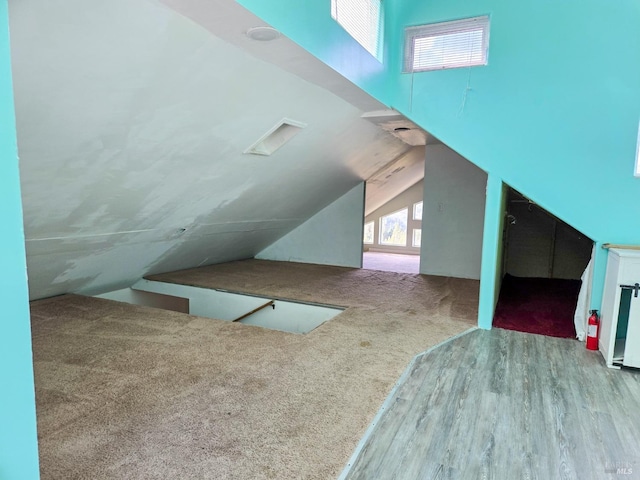 additional living space featuring carpet, vaulted ceiling, and wood finished floors