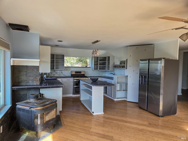 kitchen with appliances with stainless steel finishes, light wood-type flooring, tasteful backsplash, and open shelves