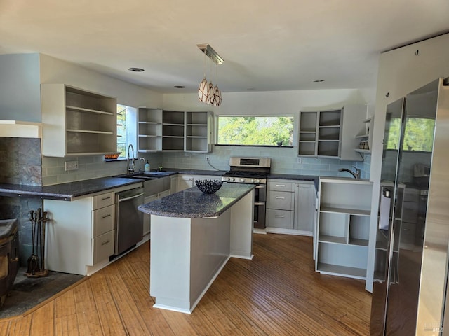 kitchen with dark wood-style floors, open shelves, backsplash, appliances with stainless steel finishes, and dark stone countertops