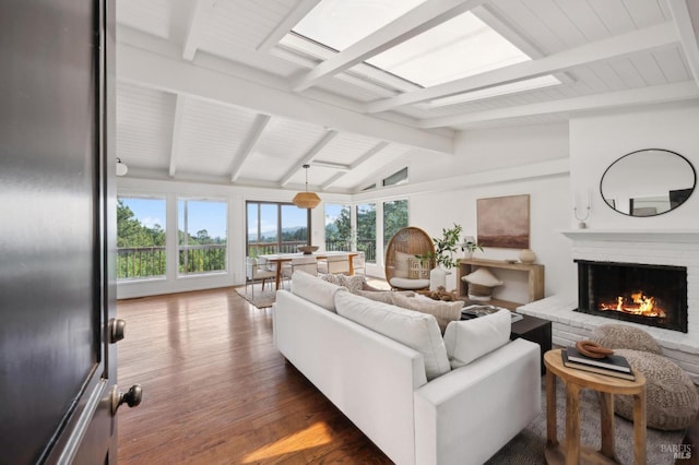 living area with lofted ceiling with skylight, dark wood-style flooring, and a fireplace