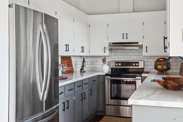 kitchen with appliances with stainless steel finishes, backsplash, under cabinet range hood, and gray cabinetry