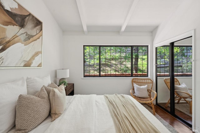 bedroom with multiple windows, wood finished floors, and beam ceiling