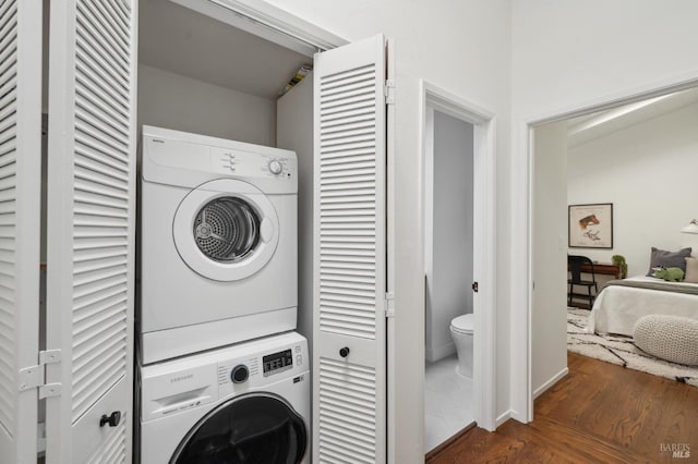 washroom with laundry area, dark wood-type flooring, and stacked washer / drying machine