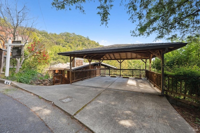 view of parking / parking lot featuring concrete driveway and a detached carport