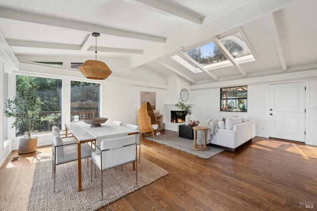 dining space featuring a lit fireplace, vaulted ceiling with skylight, wood-type flooring, and visible vents