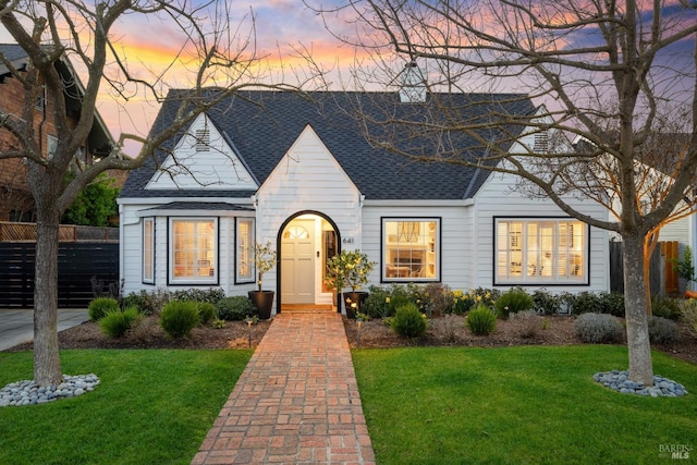 view of front of home featuring roof with shingles, fence, and a front yard