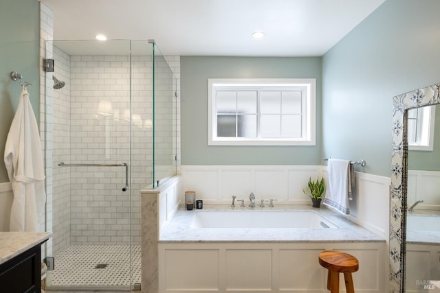 full bathroom featuring a wainscoted wall, a garden tub, a shower stall, a decorative wall, and a sink