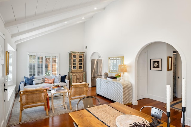 living room featuring arched walkways, beamed ceiling, and wood finished floors