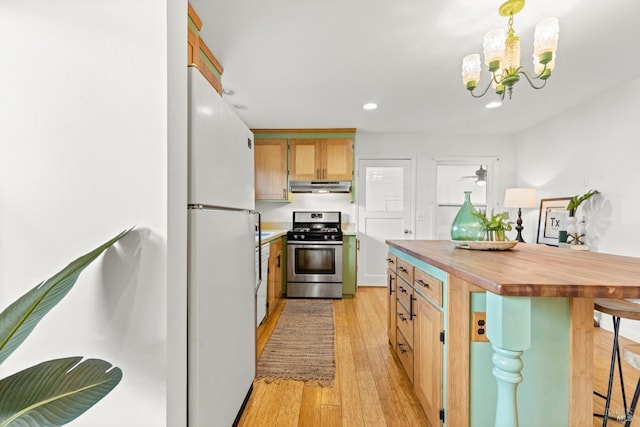 kitchen featuring stainless steel range with gas cooktop, under cabinet range hood, freestanding refrigerator, light wood-style floors, and wood counters