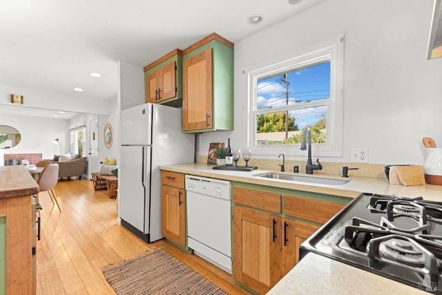 kitchen featuring a wealth of natural light, white appliances, light countertops, and a sink