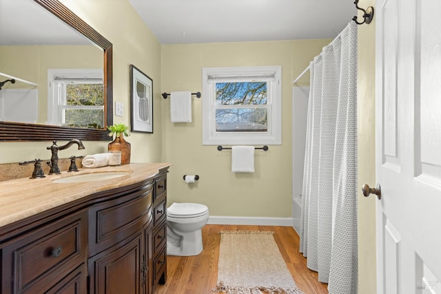 bathroom featuring toilet, vanity, baseboards, and wood finished floors