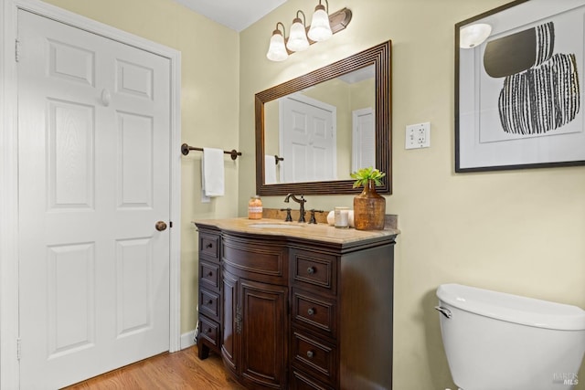 half bathroom featuring toilet, wood finished floors, and vanity