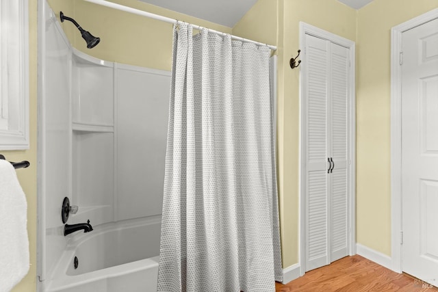 full bathroom featuring a closet, shower / bath combo with shower curtain, and wood finished floors