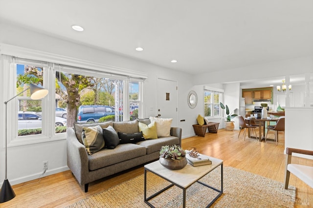 living area featuring plenty of natural light, light wood-type flooring, and an inviting chandelier