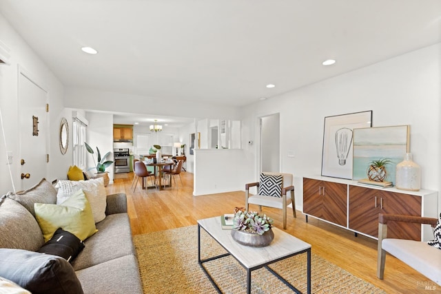 living room with recessed lighting, a notable chandelier, and light wood-style flooring