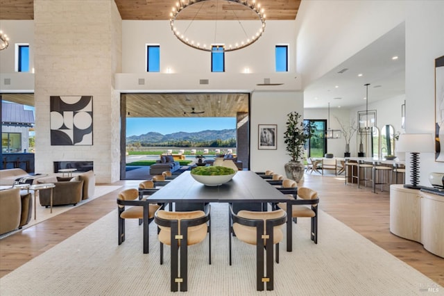 2350 Big Ranch Rd, Napa, CA 94558 - dining room featuring light wood-style flooring, a high ceiling, a chandelier, a mountain view, and a stone fireplace
