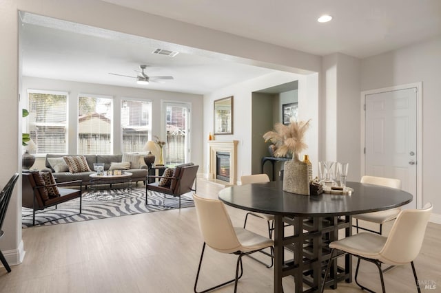 dining space with ceiling fan, recessed lighting, visible vents, light wood-style floors, and a glass covered fireplace