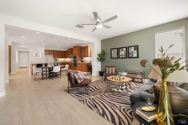 living area with recessed lighting, visible vents, a ceiling fan, light wood-type flooring, and baseboards