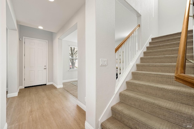 staircase featuring baseboards, wood finished floors, and recessed lighting