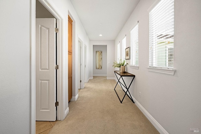 hall featuring light carpet and baseboards