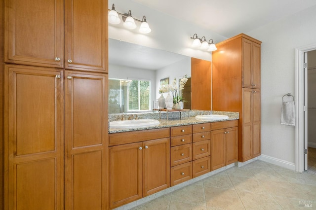 bathroom featuring double vanity, baseboards, and a sink