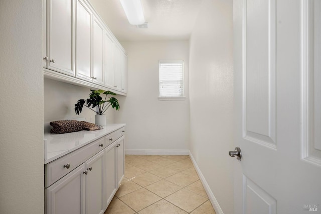 clothes washing area featuring light tile patterned floors and baseboards