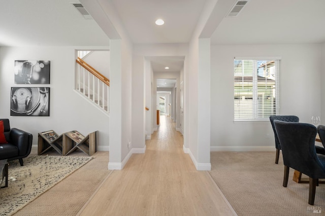 foyer with stairs, light wood-type flooring, visible vents, and baseboards