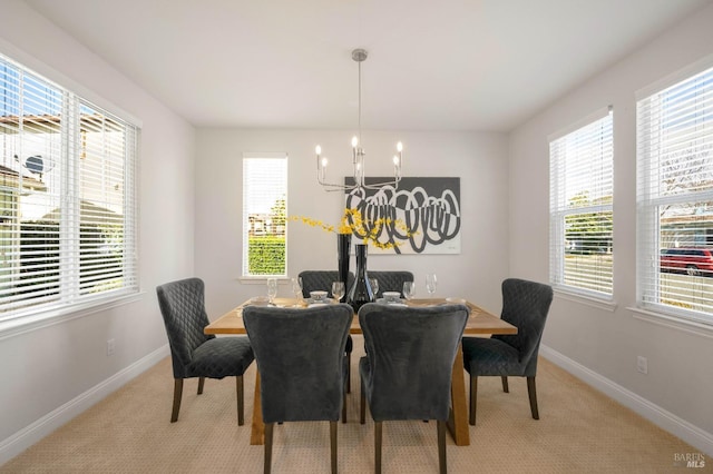 dining area with light colored carpet, plenty of natural light, baseboards, and an inviting chandelier