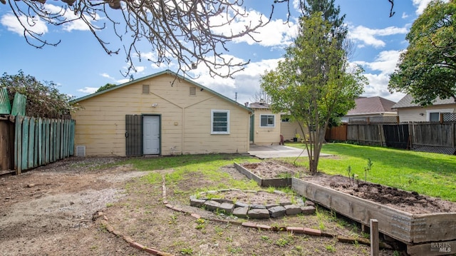 rear view of house featuring a fenced backyard, a vegetable garden, and a yard