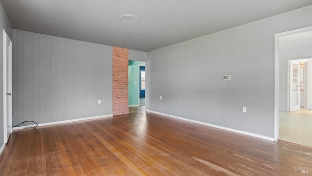 empty room with baseboards and hardwood / wood-style flooring