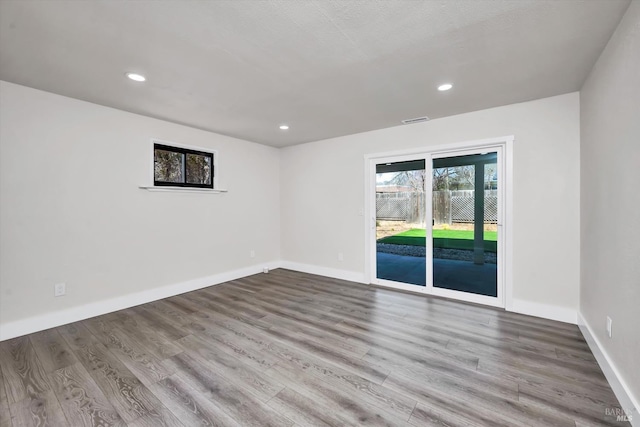 empty room featuring recessed lighting, visible vents, baseboards, and wood finished floors