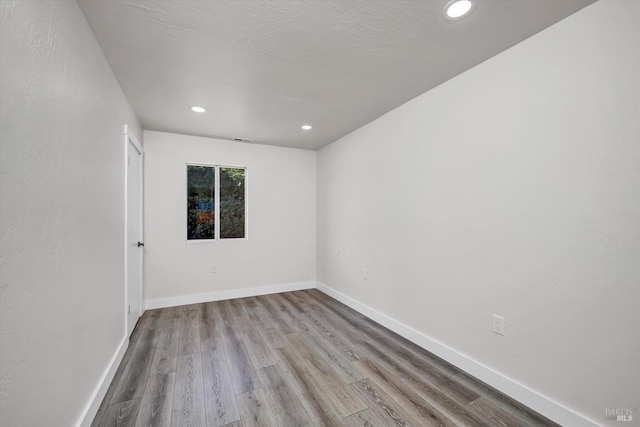 empty room with visible vents, baseboards, wood finished floors, and recessed lighting