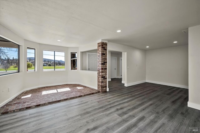 empty room with ornate columns, recessed lighting, dark wood finished floors, and baseboards