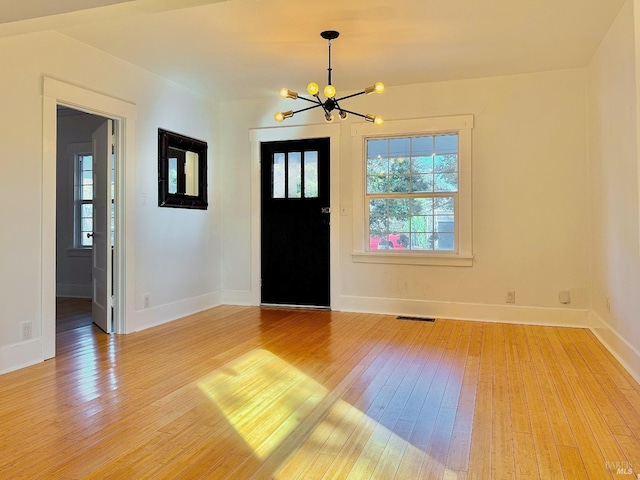 entrance foyer with visible vents, a notable chandelier, light wood-style flooring, and baseboards