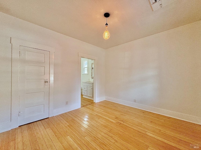 spare room featuring light wood-style floors, visible vents, and baseboards