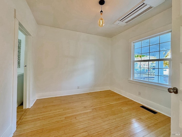 unfurnished room with light wood-style floors, visible vents, and baseboards