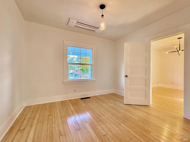 unfurnished room featuring baseboards, a notable chandelier, light wood-style floors, and visible vents