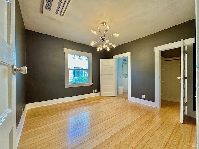 unfurnished bedroom with baseboards, light wood finished floors, visible vents, and a notable chandelier