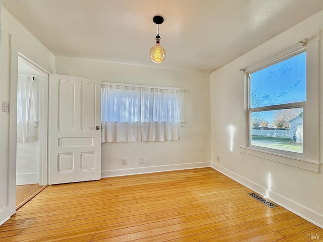 empty room with light wood finished floors, baseboards, and visible vents