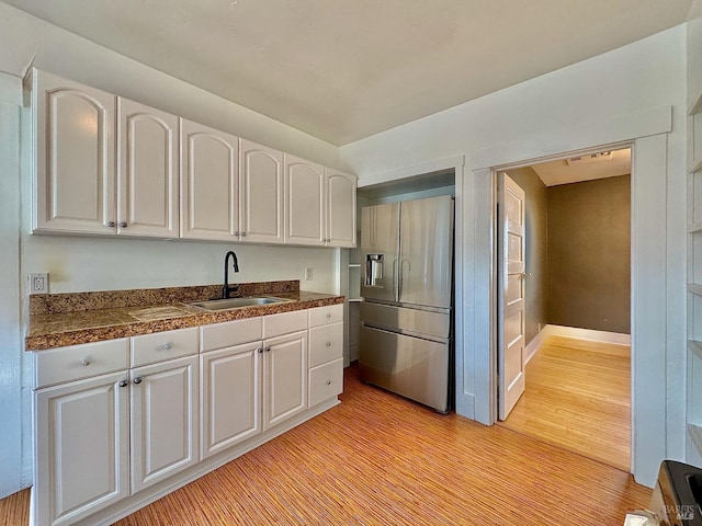 kitchen with tile counters, a sink, light wood-style floors, stainless steel fridge with ice dispenser, and white cabinets