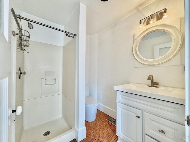 bathroom featuring toilet, visible vents, wood finished floors, a shower stall, and vanity