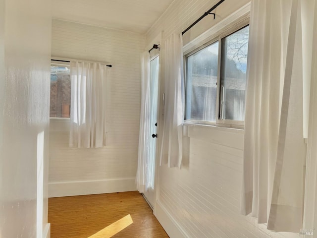 hall with baseboards, wood finished floors, and plenty of natural light