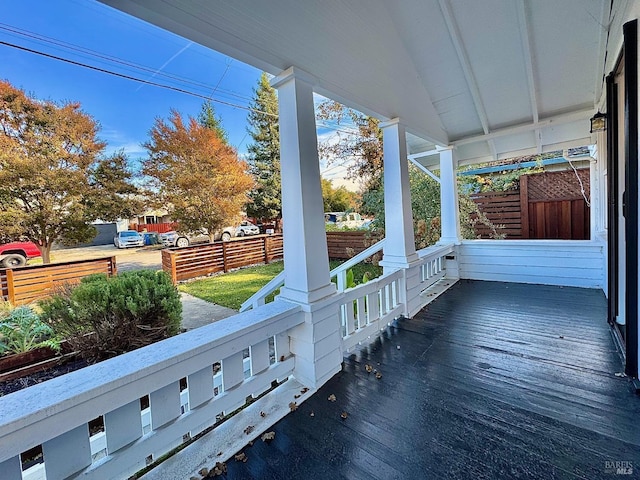 wooden terrace featuring covered porch and fence