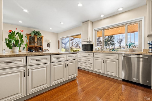 kitchen with light wood-style floors, white cabinets, dishwasher, and a sink