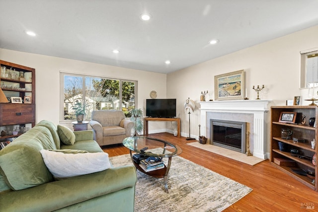 living room featuring baseboards, a tiled fireplace, wood finished floors, and recessed lighting